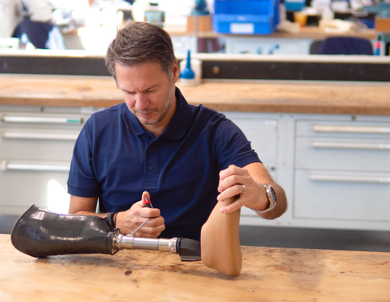 Orthopaedic technician sits in a workshop and screws on an orthosis